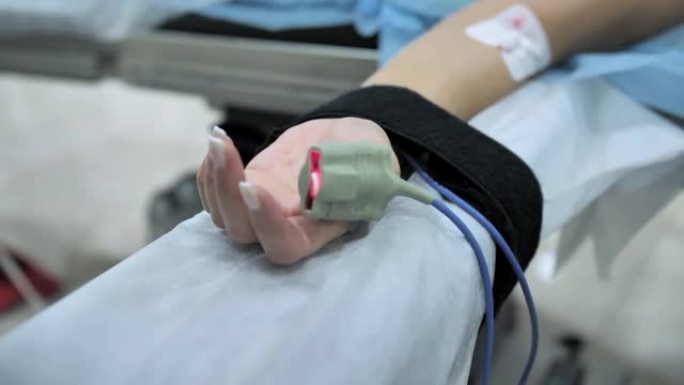 病人手指上的脉搏血氧计。手术期间安装在患者手上的外周静脉导管(PVC)。慢动作