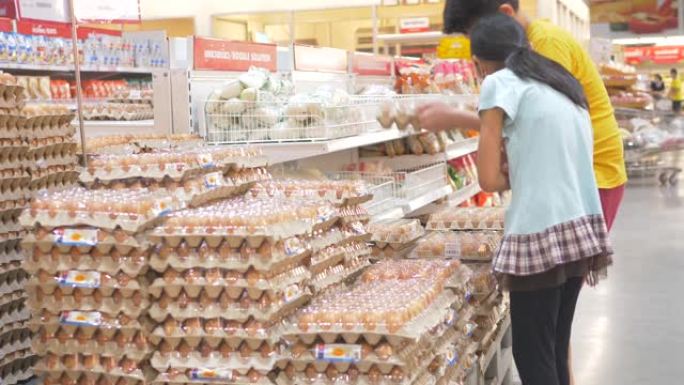新型冠状病毒肺炎期间，亚洲男孩和女孩在超市使用面膜和选择鸡蛋包。