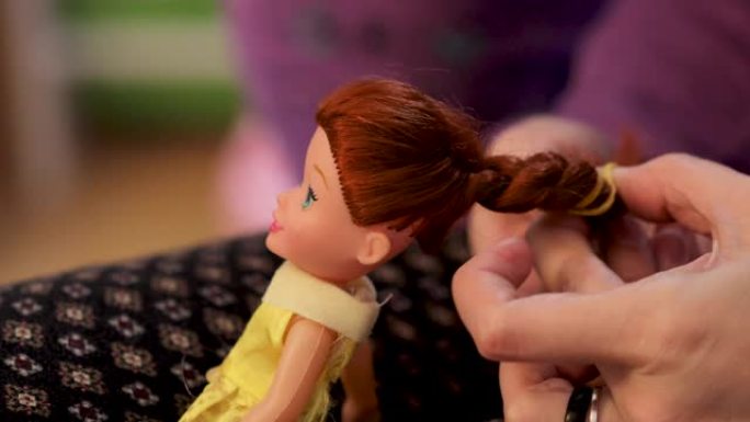 细节用母亲的手刷和整理小女儿娃娃的头发。