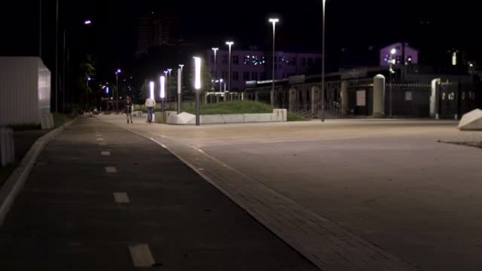 夜间城市公园和绿色小巷附近的一对夫妇骑着踏板车。库存镜头。傍晚时分沿着灯笼在公园里的小路