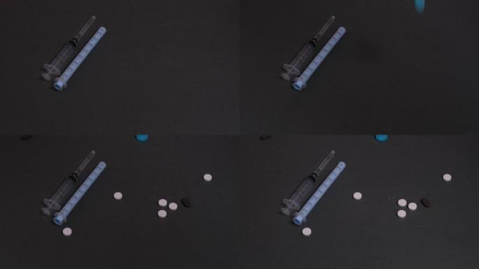 五颜六色的药丸落在灰色的背景上。在灰暗的背景下注射，药片。药物和毒瘾的概念