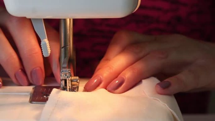 女人在打字机上缝了一块布制成的防护口罩。针架工作的特写镜头。在家工作。