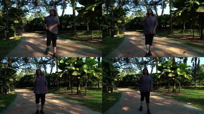 亚洲印度女性截肢与义肢行走，同时使用手机在公园