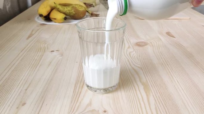 开菲尔，酸牛奶或白喝酸奶从瓶子中倒入多面玻璃中