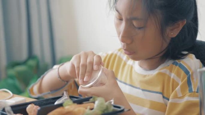 亚洲女孩在家吃饭盒里的火腿、香肠和煎蛋卷，生活方式理念。