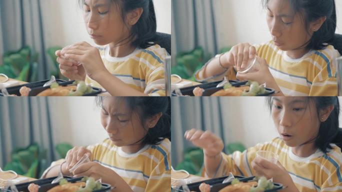 亚洲女孩在家吃饭盒里的火腿、香肠和煎蛋卷，生活方式理念。