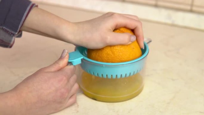 一个女人从橘子里榨汁。一个女人使用榨汁机。双手合拢。