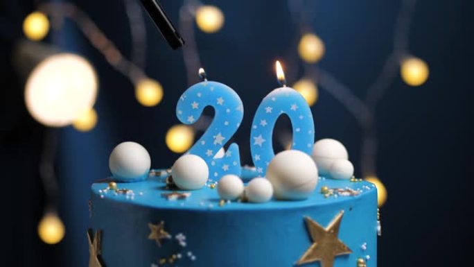 生日蛋糕编号20星星天空和月亮概念，蓝色蜡烛被打火机点燃，然后吹灭。如果需要，请在屏幕右侧复制空间。
