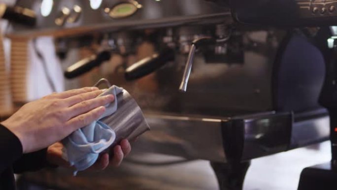 咖啡师用咖啡机煮咖啡后擦拭金属送奶员