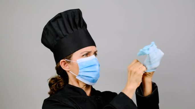 严肃女主厨餐厅老板戴上防护口罩和手套