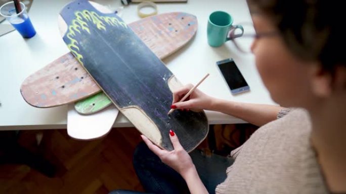 年轻的女艺术家在滑板板上素描