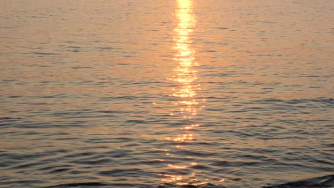 平静的海面上的日出，模糊的反射。黄色的太阳升起在海面上，太阳路径在水面上。海面上的阳光和太阳光线反射