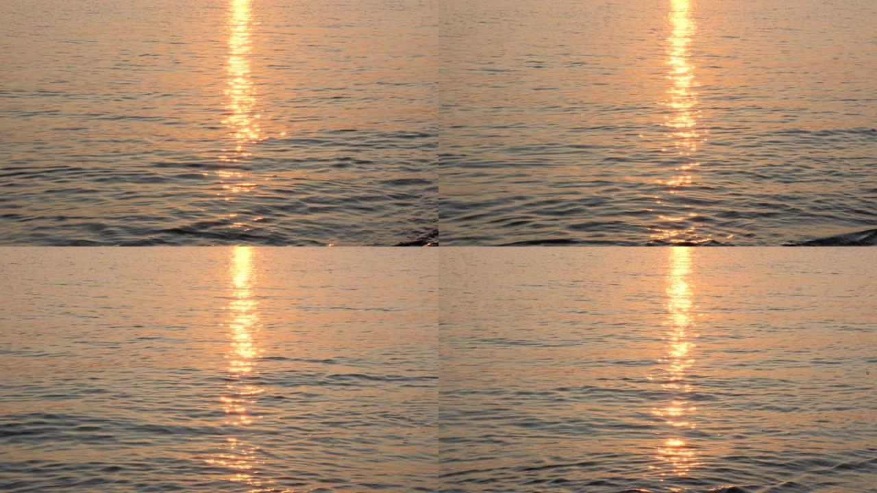 平静的海面上的日出，模糊的反射。黄色的太阳升起在海面上，太阳路径在水面上。海面上的阳光和太阳光线反射