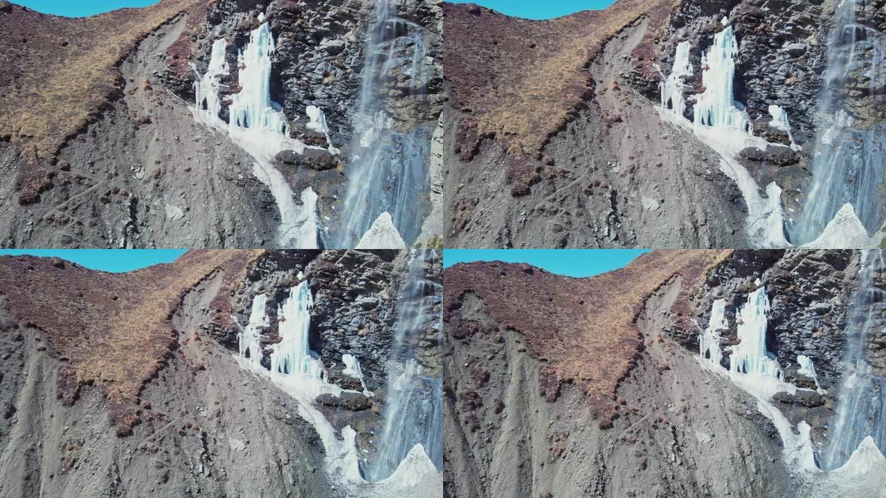 令人惊叹的山瀑布从岩石卵石悬崖上落下，冰柱结冰