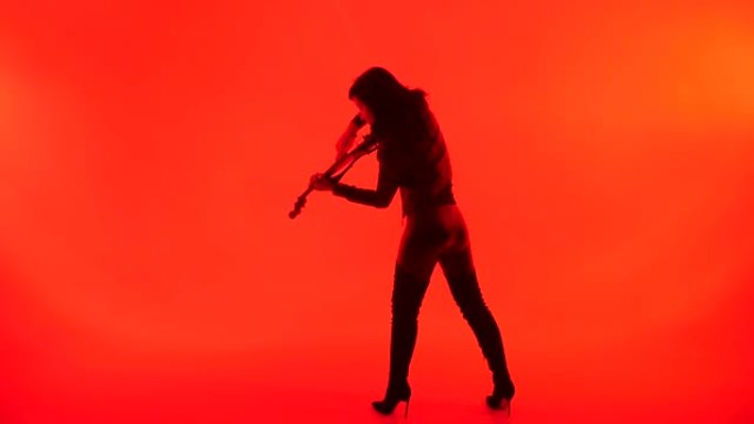 年轻的小提琴手在红色背景上演奏小提琴，孤立