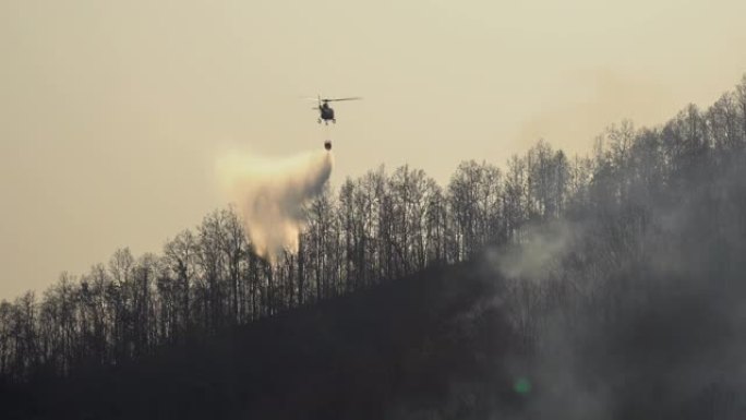 消防员直升机在森林大火中从水桶中滴水