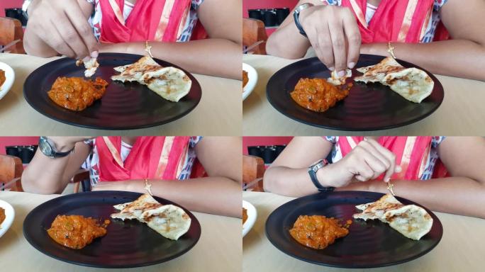 双手撕下黄油naan，然后在as餐厅的黑色盘子里用鸡肉tikka黄油masala肉汁吃。