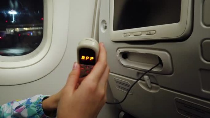 女孩拿着飞机上娱乐系统的遥控器