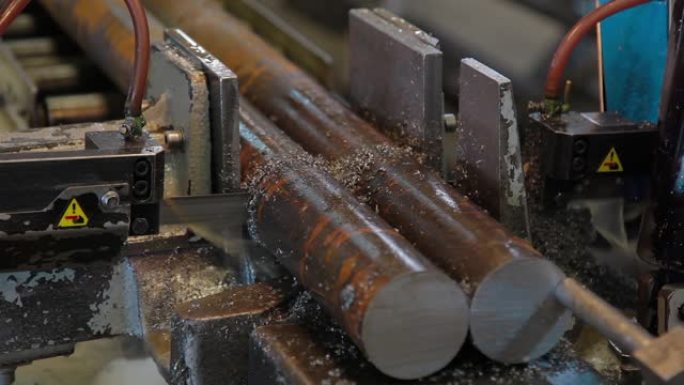 工业锯床切割材料棒。带锯机用冷却液切割原始金属。