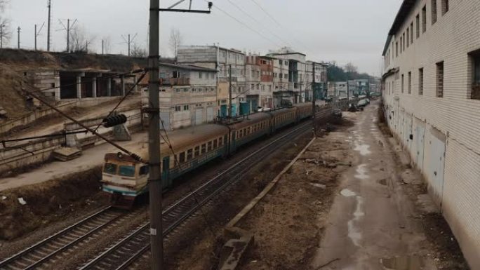 生锈的电动火车像贫民窟一样沿着城市车库行驶。