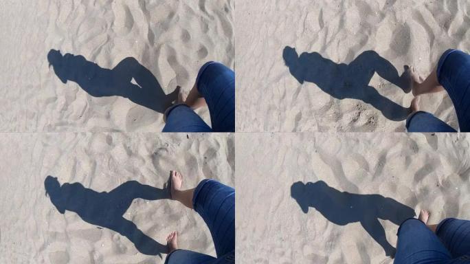 在岸上的沙滩上散步的女孩的黑影