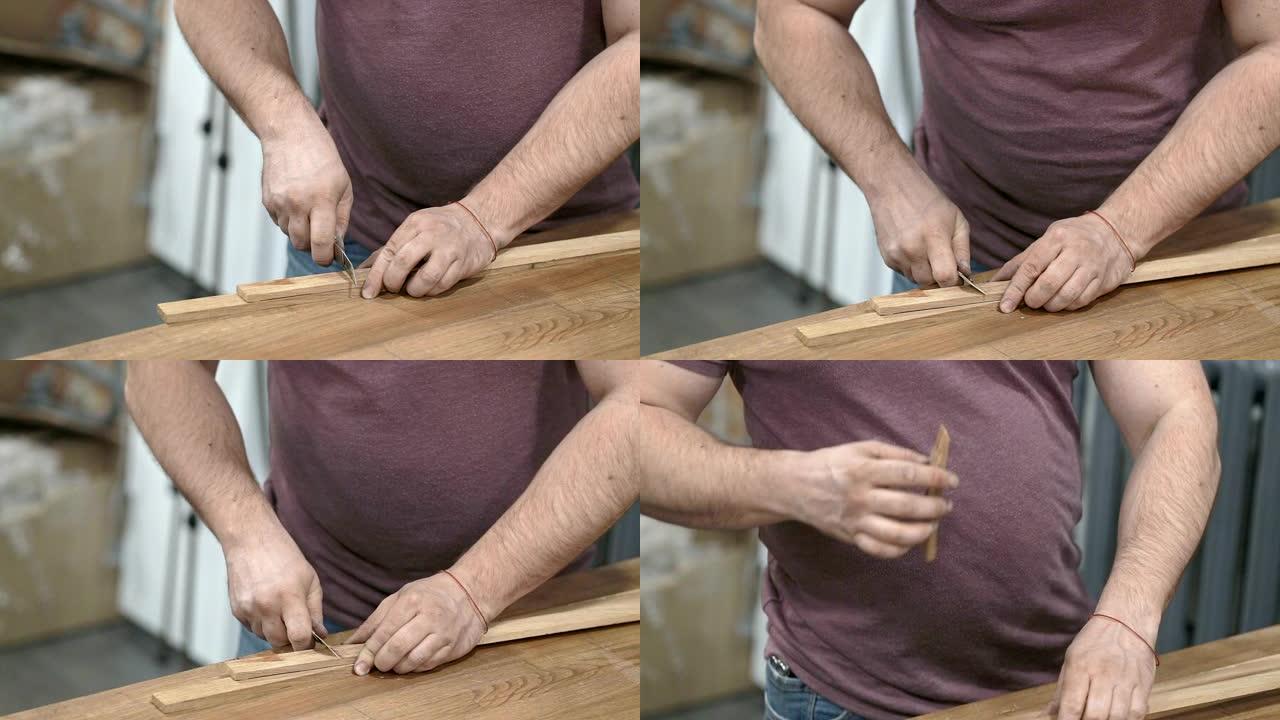 男人的手用小刀切开一块木板。