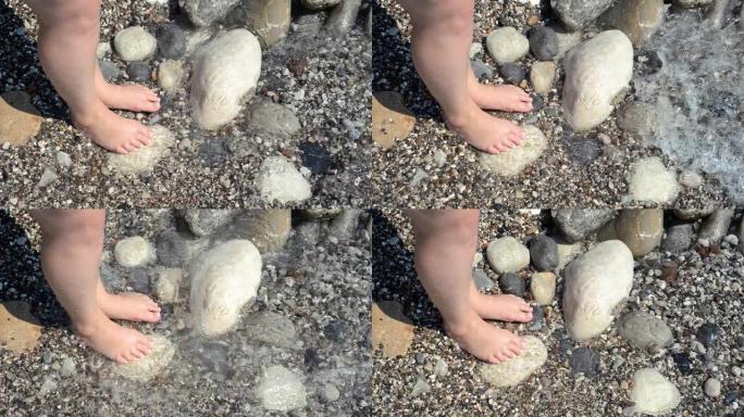 石滩和一对女人的脚被海浪冲刷