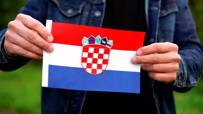 一名男子在户外举着克罗地亚国旗。独立日，或国定假日的概念