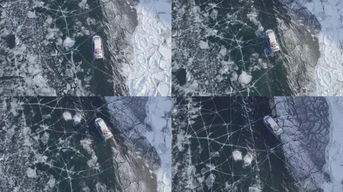 Khivus船的航拍镜头气垫船船在气垫上滑行在冰冻的贝加尔湖上驶向奥尔洪岛。冰雪景观上美丽的裂缝图案