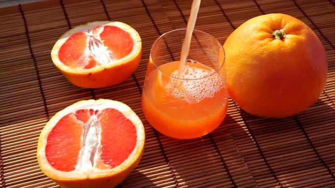 葡萄柚汁爆成玻璃杯。柑橘维生素汁在一个透明的玻璃水果。饮食饮料