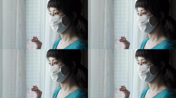 戴着外科口罩的亚洲妇女的室内肖像向窗外看