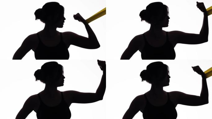 年轻运动女性的轮廓轮廓用弹性橡皮筋在白色孤立的背景上锻炼手臂肌肉，运动女孩训练，概念女性美丽和健康的