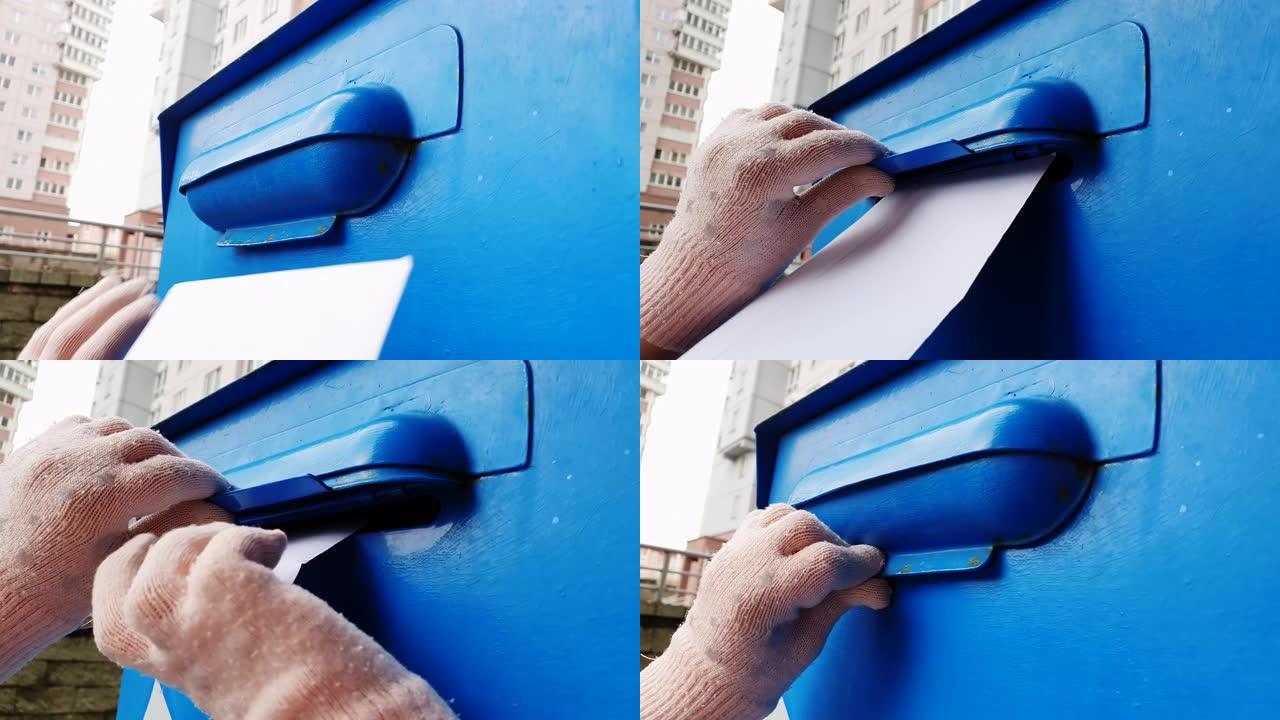 一个戴着手套的孩子在蓝色邮箱里扔了一封信。