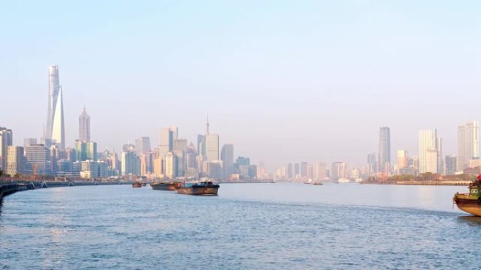 晴天，上海天际线城市景观背景下，在黄浦江上航行的货船船队的延时镜头，4k视频。