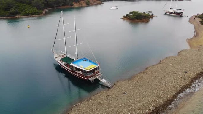 土耳其水蓝色水中的船的天线，天堂般的感觉海滩上清澈的海水，海滩蓝白色的沙子向下拍摄