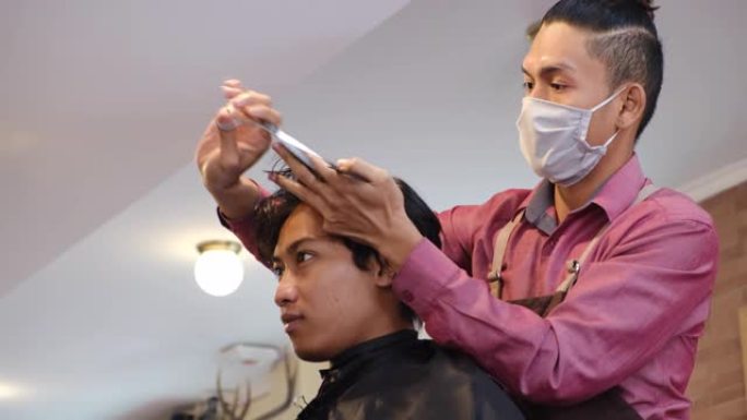 亚洲男子在理发店或发廊进行发型设计和理发。主人在理发店剪头发