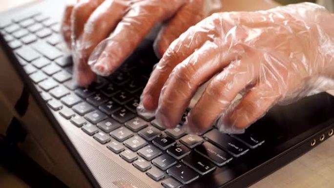 在家远程工作。戴着抗菌手套的手在笔记本电脑键盘上打字。由于冠状病毒而检疫。病毒流行的预防措施。呆在家