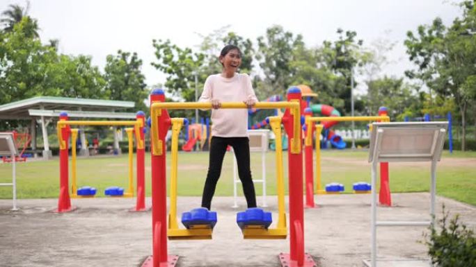 快乐的亚洲女孩在公园户外使用健身器材，慢动作。