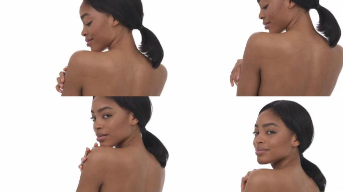 美丽的裸非洲女人的背影与慵懒的样子温柔地触摸她的手和肩膀的丝绸般的皮肤。诱人的概念。孤立，在白色背景