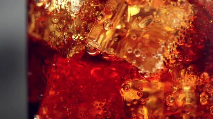 玻璃的微距镜头，冰块和碳酸可乐汽水饮料的气泡，特写