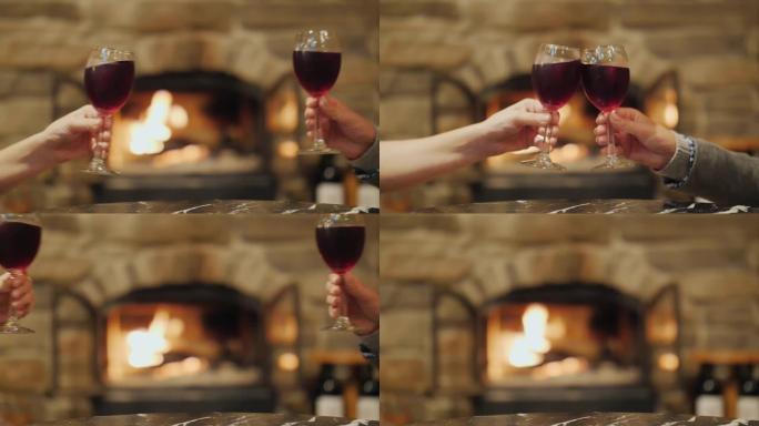 在燃烧的壁炉的背景上碰碰眼镜。4k慢动作视频