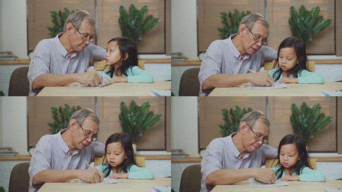 亚洲高级祖父在家教孙女在客厅做作业