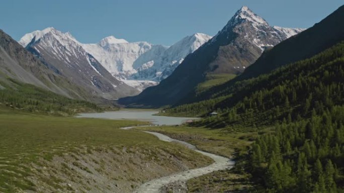 耸立在森林湖上的巨大雪山，骑马者越过野河