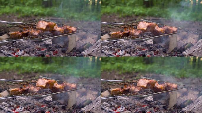 大自然森林里的烤肉。和朋友一起度假。厨师用刀将肉从烤架上移开，将其翻过来，看着烹饪。
