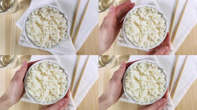 圆碗煮白米饭。女性手握板