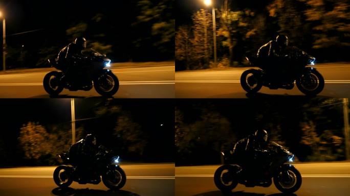 戴着头盔的年轻人在晚上的城市街道上快速骑现代运动摩托车。摩托车手在夜间空旷的道路上骑摩托车。开车的人