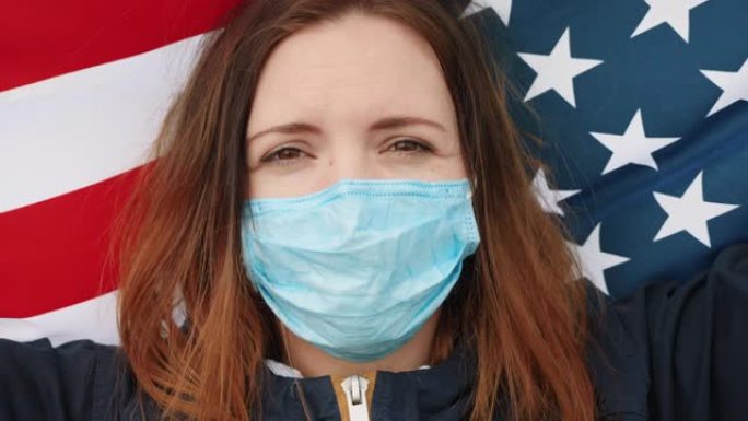 戴着医用面具的女孩举着美国国旗。特写脸