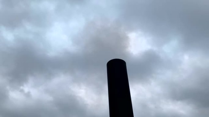 烟雾来自黑色的工厂烟囱，面对灰色的多云天空。木材加热产生的烟雾。大气污染。环境问题。