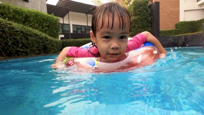 快乐的亚洲小女孩在夏天和家人在游泳池玩耍。度假中的家庭生活方式。