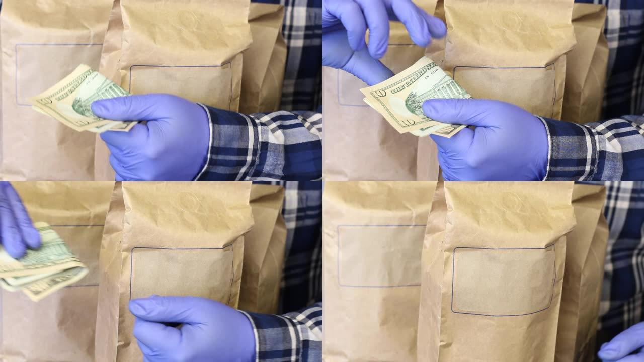 装有食物的纸袋。一个戴着橡胶手套的人手里拿着美元钞票，为订单付款。疫情期间送货上门。